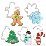 Cinq emporte-pièces de Noël en métal avec biscuits décorés : bonhomme, flocon, sapin, bonhomme de neige, canne