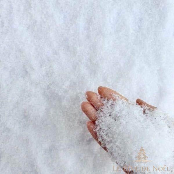 Gros plan sur une main plongée dans de la neige artificielle blanche et texturée
